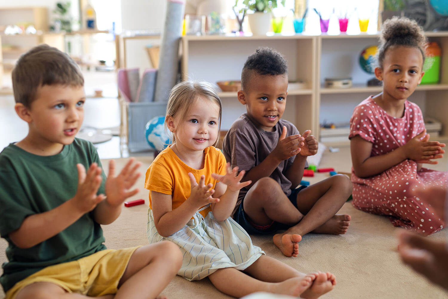 Diverse preschool children develop Kindergarten readiness and engage in Early Childhood Development through clapping hands during preschool education.