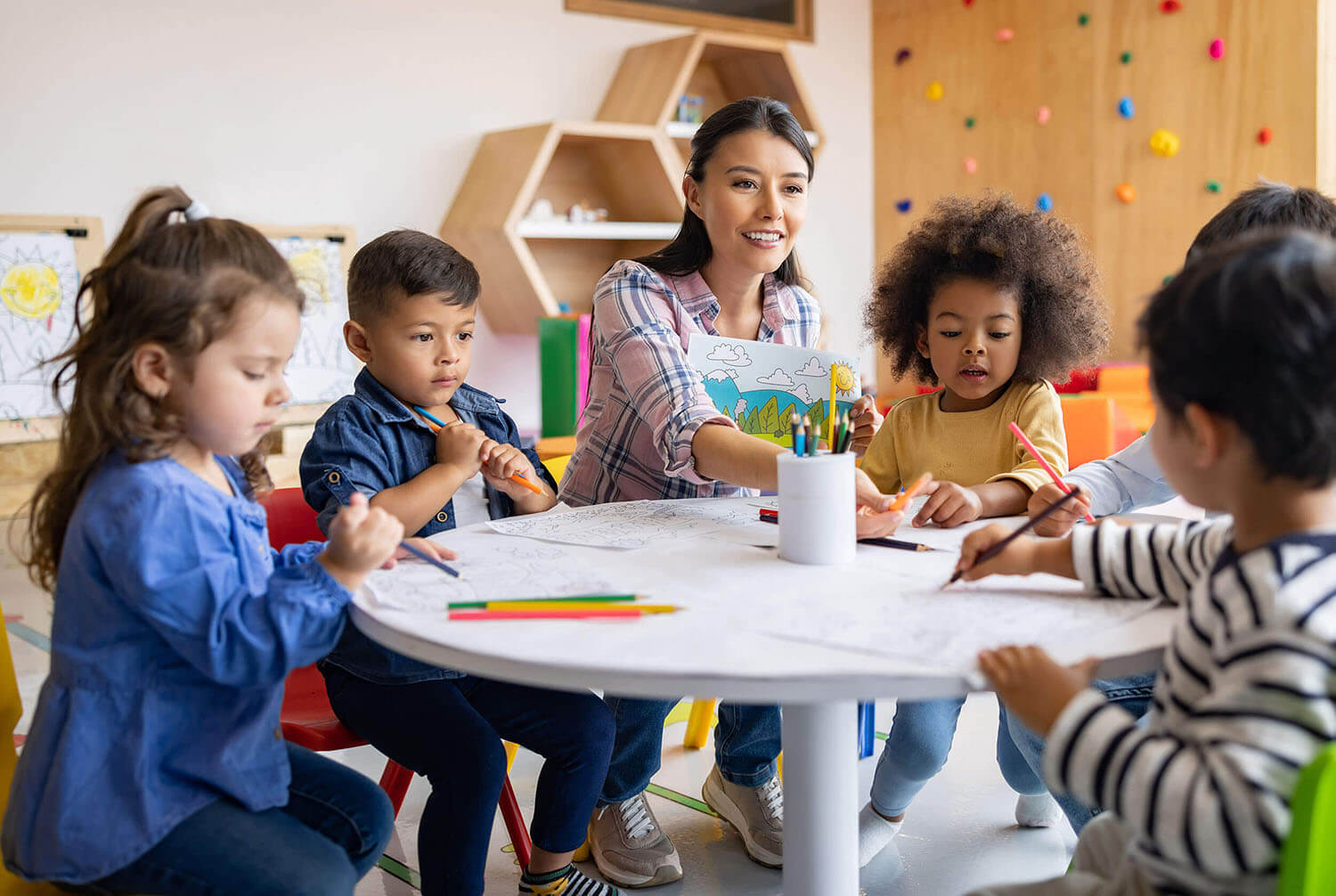 A diverse group of preschool children gather around a teacher as she reads a book in a safe and nurturing environment. Early childhood development and learning through play are encouraged.